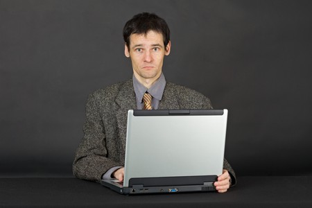 A young man working with laptop computer on a dark backgroundの写真素材