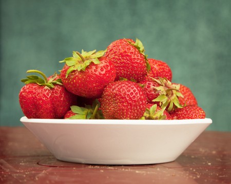 Ripe berries of a strawberry in a porcelain plate on a tableの写真素材