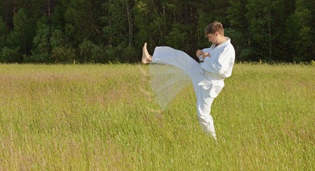 The man in a kimono fulfills blows by feet in the fieldの写真素材