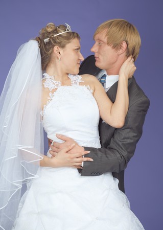 Romantic groom and the bride pose on a lilac backgroundの写真素材
