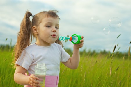 The little girl starts soap bubbles in the fieldの写真素材