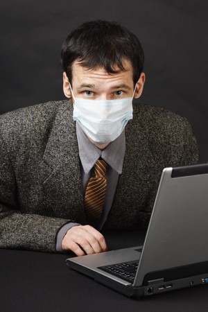 The young man in a medical mask works in the Internetの写真素材