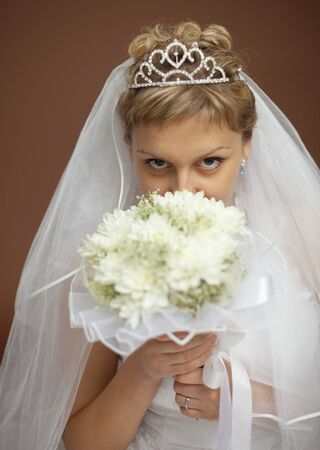 Portrait of the bride with a bunch of flowers at the face on a brown backgroundの写真素材