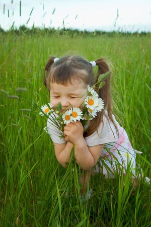 The little girl embraces wild flowers - chamomilesの写真素材
