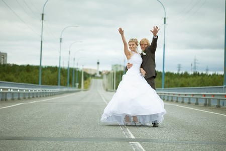 Newly married have fun standing on country highwayの写真素材