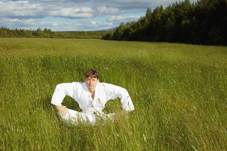 The young man sits in a grass in the fieldの写真素材
