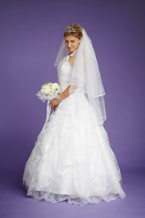 Young beautiful bride in a white dress on a purple backgroundの写真素材