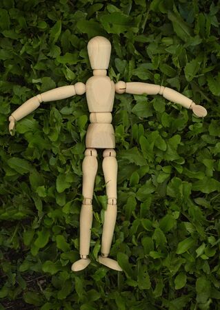 Toy wooden man lying on the grassの写真素材