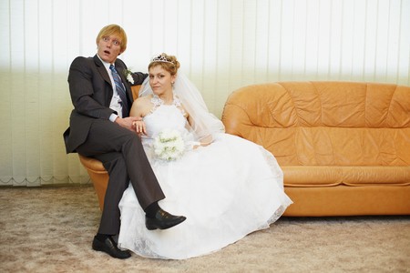 Amusing groom and the bride pose sitting on an armchairの写真素材