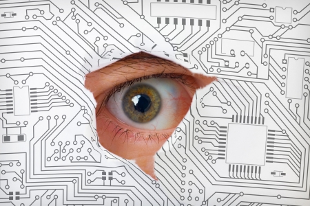 Human eye looking through a hole in the electronic circuitの写真素材