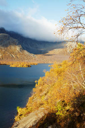 Coast mountain lake among the autumn forestの写真素材