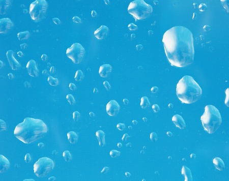 The glass surface with large water droplets on a blue backgroundの写真素材