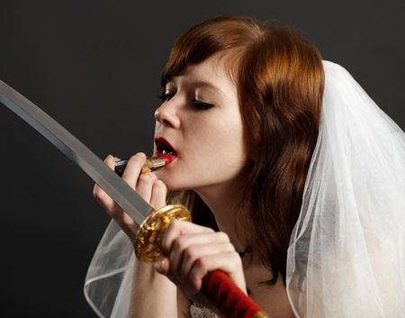 Bride lipstick using the reflection in the sword on dark backgroundの写真素材