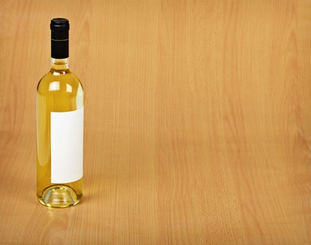 A bottle of white wine stands on a wooden tableの写真素材