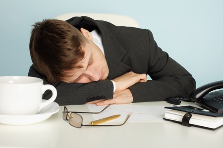 A young office worker was tired and fell asleep at the tableの写真素材