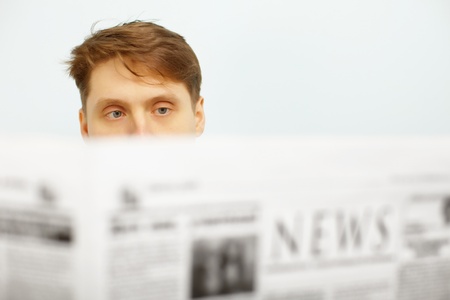 A young man reads the news in the newspaperの写真素材