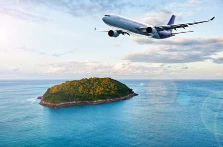 A passenger plane flies over tropical islandの写真素材