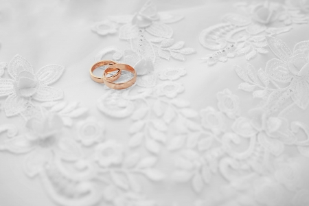 Two gold wedding rings on white dress backgroundの写真素材