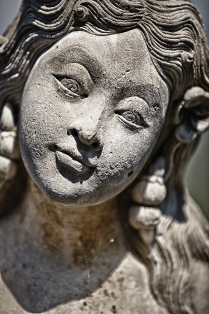 Face of stone old grey female statue with gentle smileの写真素材