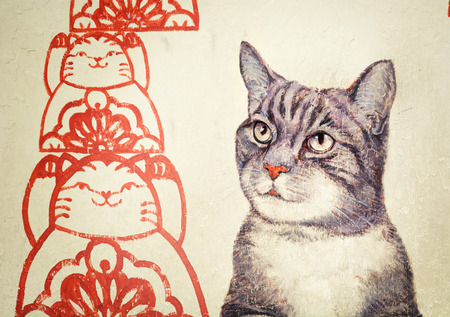 MALAYSIA, PENANG, GEORGETOWN - CIRCA JUL 2014: Mural with realistic picture of a tortoiseshell cat beside red, stylized rendering of cats in a patternのeditorial素材