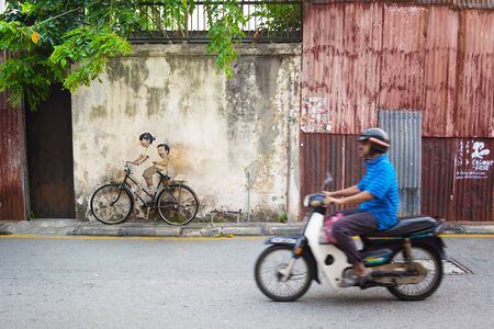 MALAYSIA, PENANG, GEORGETOWN - CIRCA JUL 2014: Real bicycle juxtaposed over lifesize mural of children riding a bicycle.のeditorial素材