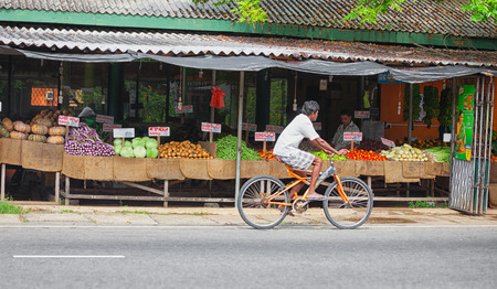SRI LANKA - CIRCA APR 2013: vegetable outdoor market. cyclist pass through the marketplaceのeditorial素材
