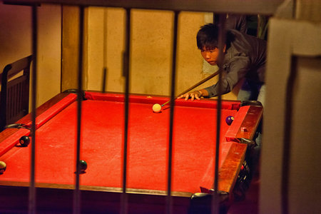 LUANG PRABANG, LAOS - CIRCA DEC 2013: view through window in billiard. The asian man plays...