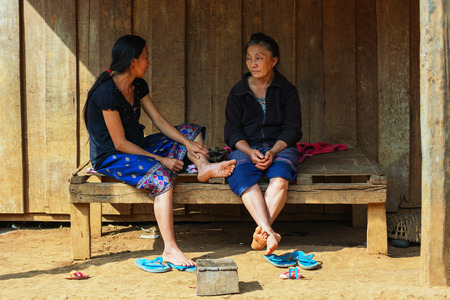 LUANG PRABANG, LAOS - CIRCA DEC 2013: Local aged woman relaxing near the houseのeditorial素材