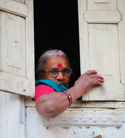 UDAIPUR, RAJASTHAN, INDIA - CIRCA NOV 2012: Woman looks to the street from the houseのeditorial素材