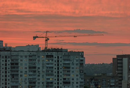 Sunset in the city. Red sky with clouds, skyscrapers and construction craneの写真素材