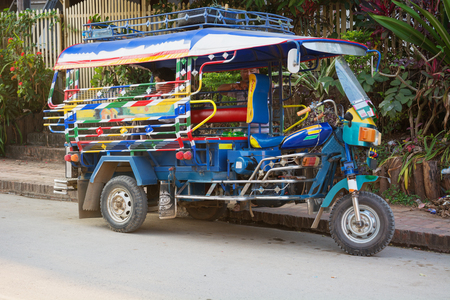 LUANG PRABANG, LAOS - CIRCA DEC 2013: Colorful Tuk-Tuk Taxi Parked curbside in Luang Prabang, Laosのeditorial素材