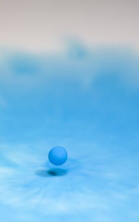 It is a drop of blue colored milk caught just before impactの写真素材