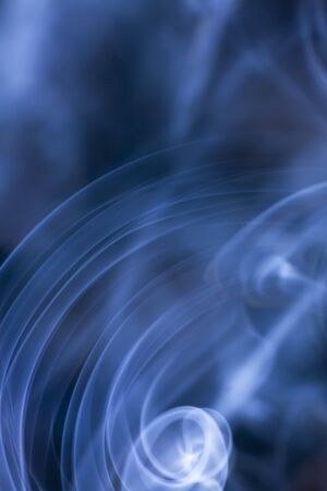 Spirals of Smoke in focus with a blurred backgrouondの写真素材