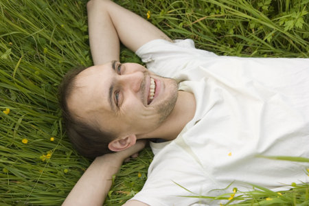 The man lies on a grass and smilesの写真素材