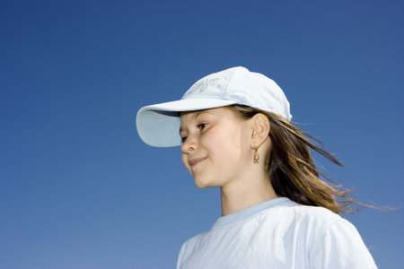 The smiling girl in a cap against a dark blue clear skyの写真素材