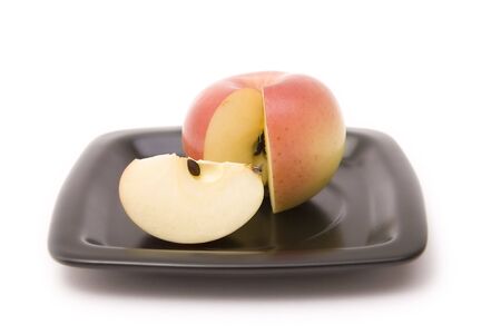 Apple and its segment on a black plate on a white backgroundの写真素材