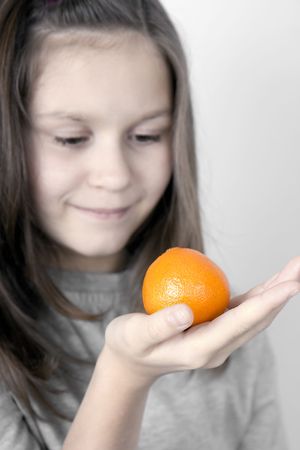 The girl holds a tangerine on a palmの写真素材