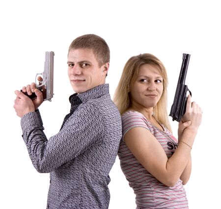 young man and woman standing back to back with the pistols in their handsの写真素材