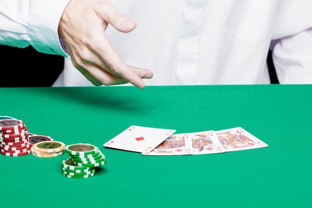 player's hand with cards and poker chips on a green tableのeditorial素材