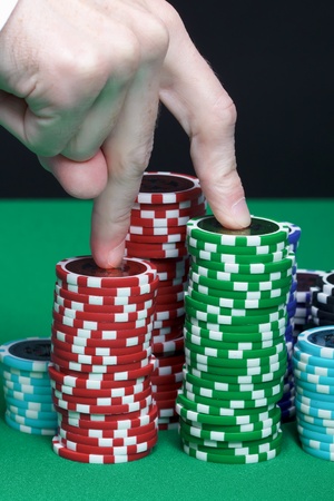 Men's fingers are marching up the pile of playing chipsの写真素材