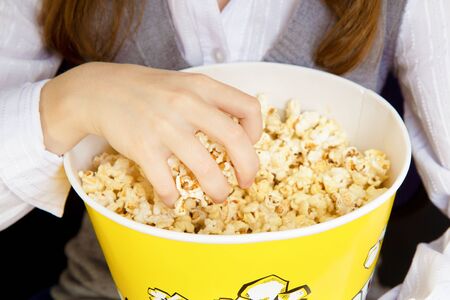 child's hand in a bucket of popcornの写真素材