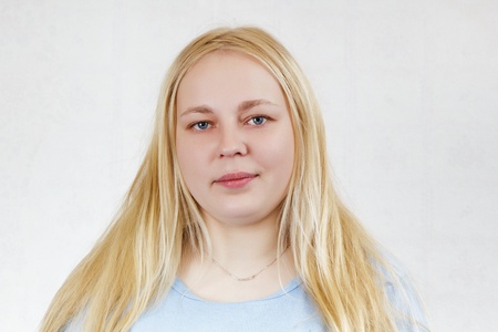 chubby blonde girl in a blue shirt on a white background. portraitの写真素材