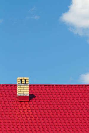 Red roof with chimney against the skyの写真素材