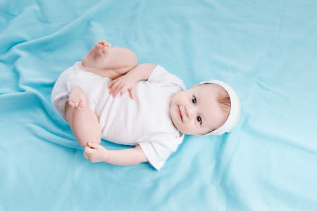 Baby in hat lying on a blue plaidの写真素材