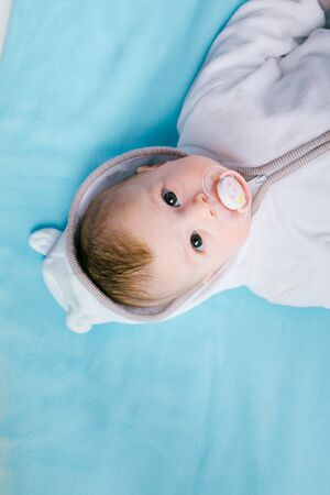 Baby in the hood on a blue blanketの写真素材