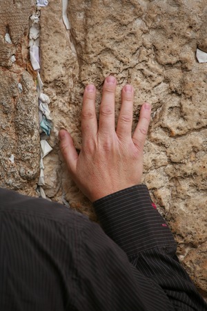 Hand with shoulder of praying men on the Western Wall with wishes in Jerusalem.の写真素材