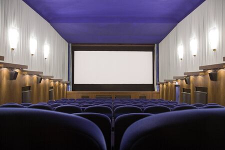 Empty cinema auditorium with line of chairs and projection screen. Ready for adding your own picture. Front view.の写真素材