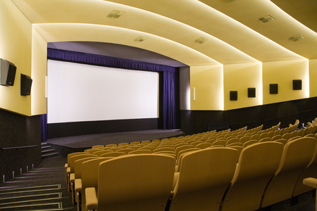 Empty cinema auditorium with line of chairs and projection screen. Ready for adding your own picture. Side view.の写真素材