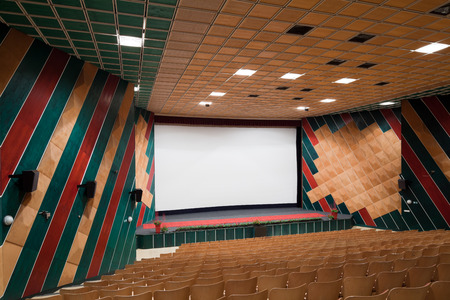 PR (property release) available. Empty cinema auditorium with line of chairs and projection screen. Ready for adding your own picture. Side view.の写真素材