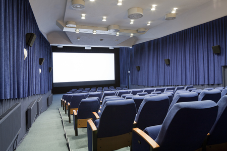 PR (property release) available. Empty cinema auditorium with line of chairs and projection screen. Ready for adding your own picture. Side view.の写真素材